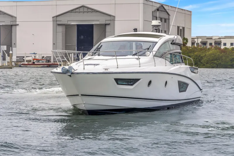 Slide: The Image of 2019 Beneteau Gran Turismo 46 yacht cruising near a marina, showcasing sleek design. - 76