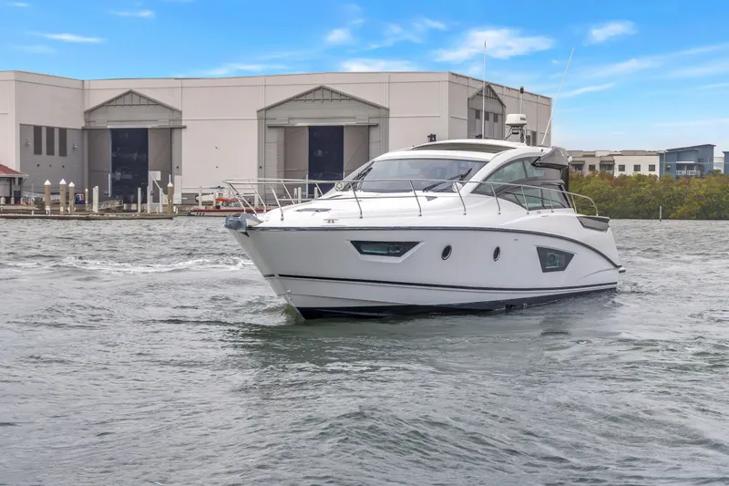 Slide: The Image of 2019 Beneteau Gran Turismo 46 yacht cruising near a marina under a clear blue sky. - 77