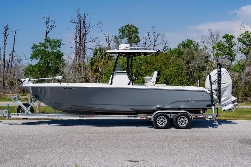 The Image of 2023 Pathfinder 2700 Open boat on trailer, parked outdoors with trees in background. - 1