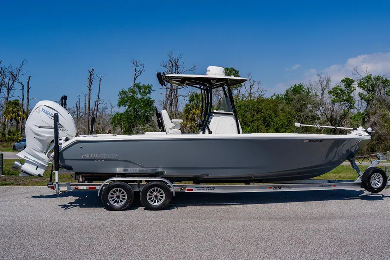 Slide: The Image of 2023 Pathfinder 2700 Open boat on trailer, side view, outdoors with trees in background. - 2