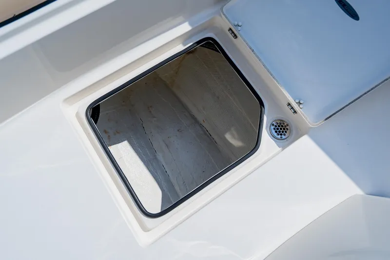 Slide: The Image of Open storage compartment on 2023 Pathfinder 2700 Open boat, featuring a drain and white interior. - 24