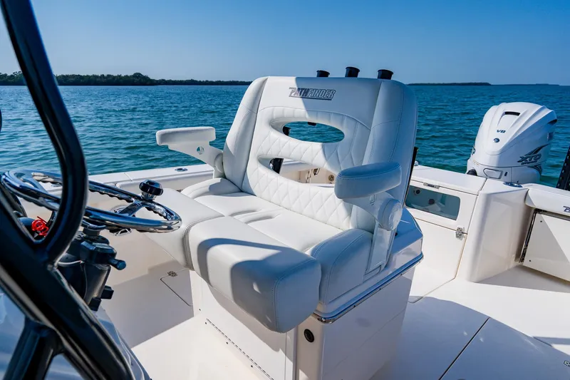 Slide: The Image of 2023 Pathfinder 2700 Open boat interior with luxurious seating and steering wheel, on calm water. - 38
