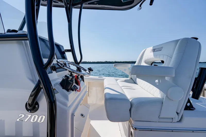 Slide: The Image of 2023 Pathfinder 2700 Open boat interior with steering wheel and seating, on calm water. - 40