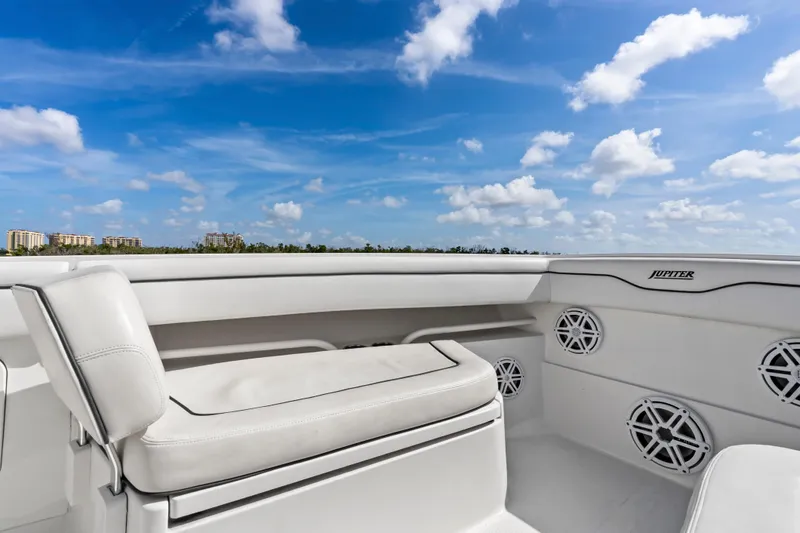Slide: The Image of 2015 Jupiter 34 HFS boat interior with white seating and speakers under a blue sky. - 13