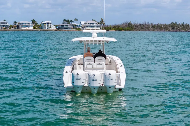 Slide: The Image of 2015 Jupiter 34 HFS boat cruising on blue water near coastal homes. - 2