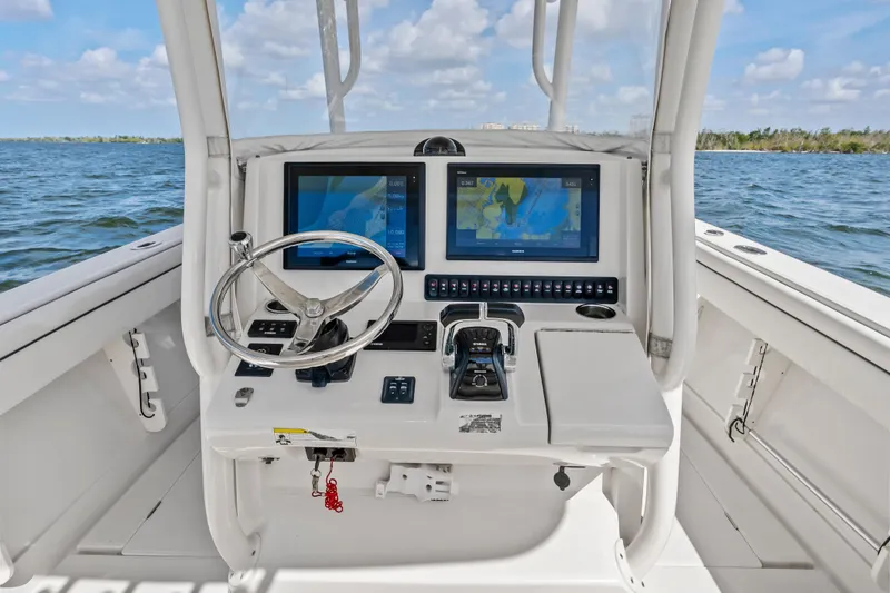 Slide: The Image of 2015 Jupiter 34 HFS boat helm with dual navigation screens and steering wheel on open water. - 20