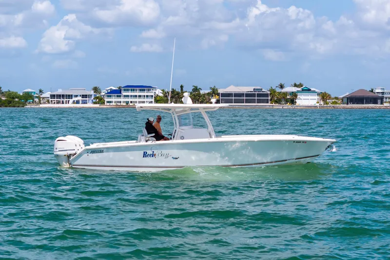 Slide: The Image of 2015 Jupiter 34 HFS boat cruising on turquoise water near coastal homes. - 3