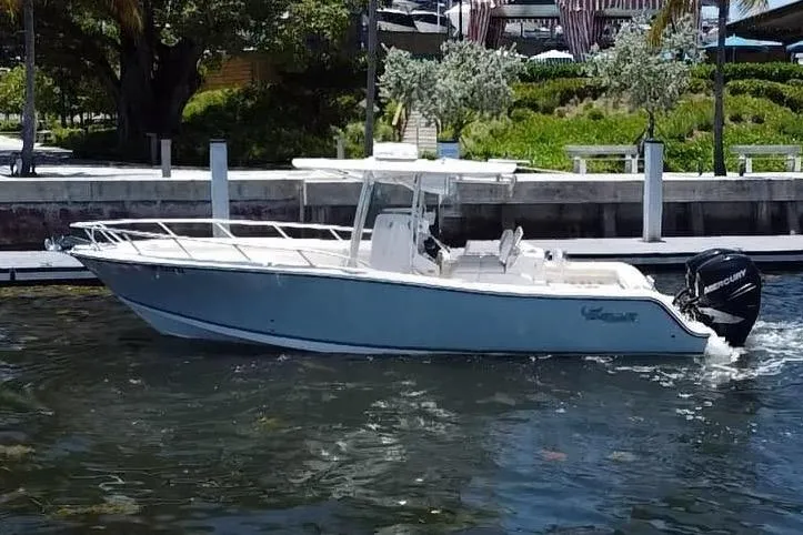 The Image of 2014 Mako 284 CC boat cruising near a tropical dock with palm trees. - 0