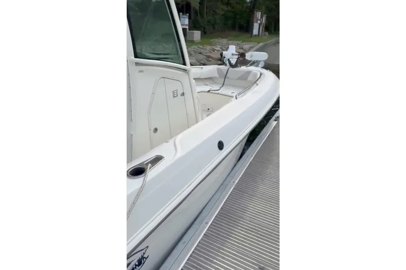 Slide: The Image of 2023 Boston Whaler 250 Outrage boat docked, showcasing sleek white design and spacious deck. - 5