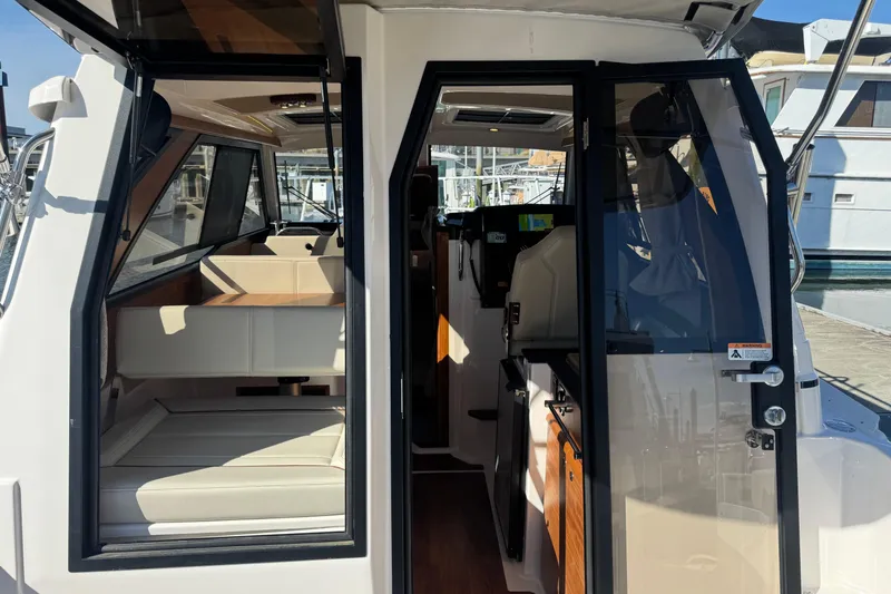 Slide: The Image of 2026 Cutwater C-248 Coupe interior view, showcasing seating and helm area at a marina. - 5