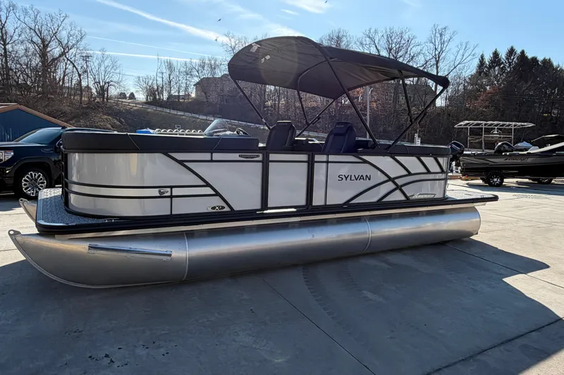 Slide: The Image of 2026 Sylvan Mirage X X3 pontoon boat parked outdoors on a sunny day. - 2