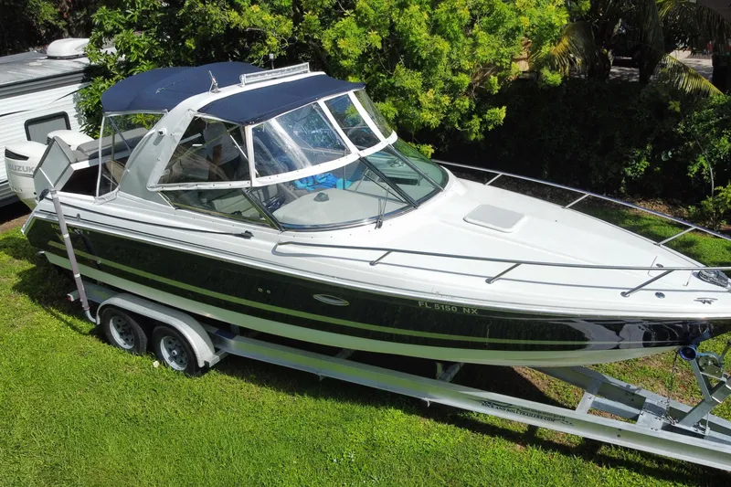 Slide: The Image of 2005 Formula 280 Sun Sport boat on trailer, parked on grass, surrounded by trees. - 16