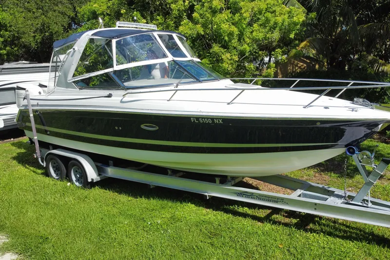 Slide: The Image of 2005 Formula 280 Sun Sport boat on trailer, parked on grass, surrounded by trees. - 17