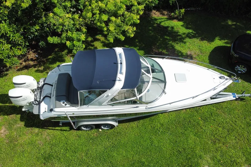 Slide: The Image of 2005 Formula 280 Sun Sport boat on trailer, parked on grass, with twin Suzuki outboard engines. - 18