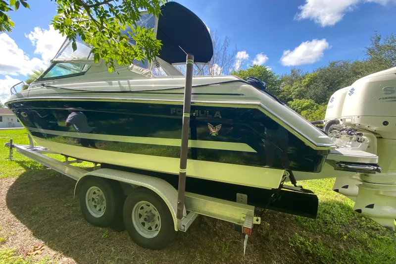 Slide: The Image of 2005 Formula 280 Sun Sport boat on trailer, parked on grass under a sunny sky. - 61