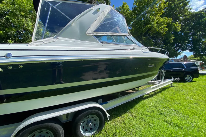 Slide: The Image of 2005 Formula 280 Sun Sport boat on trailer, parked on grass, with trees in background. - 7