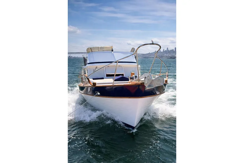Slide: The Image of 1978 Marine Trader Europa yacht cruising on open water, city skyline in background. - 1