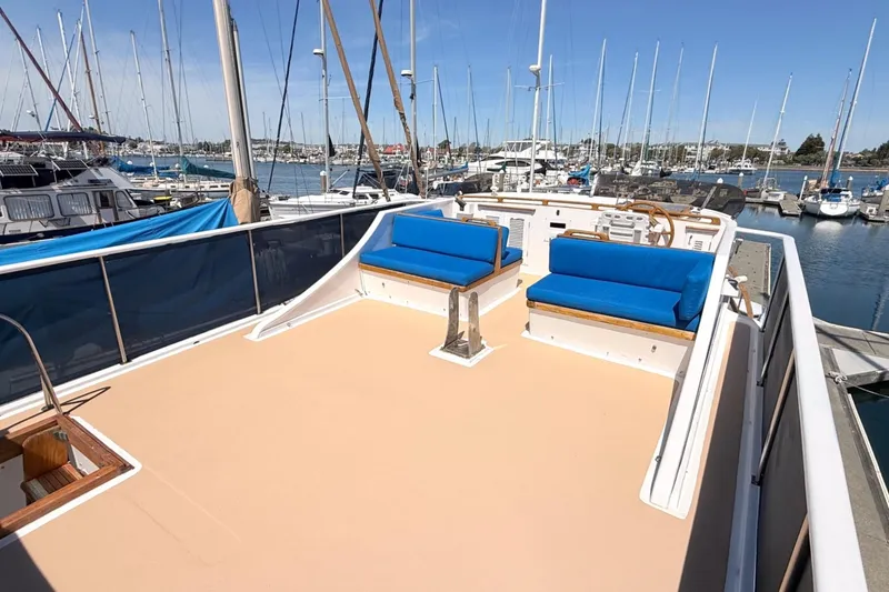 Slide: The Image of 1978 Marine Trader Europa yacht deck with blue seating, docked in a marina. - 13