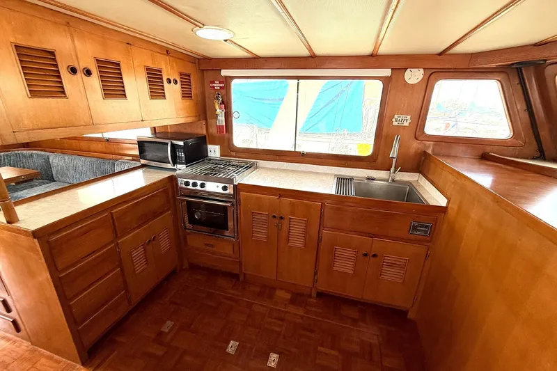 Slide: The Image of 1978 Marine Trader Europa yacht kitchen with wood cabinetry, stove, microwave, and sink. - 18