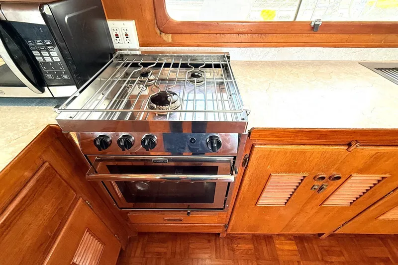 Slide: The Image of 1978 Marine Trader Europa kitchen with stove, oven, and microwave in wooden cabinetry. - 19