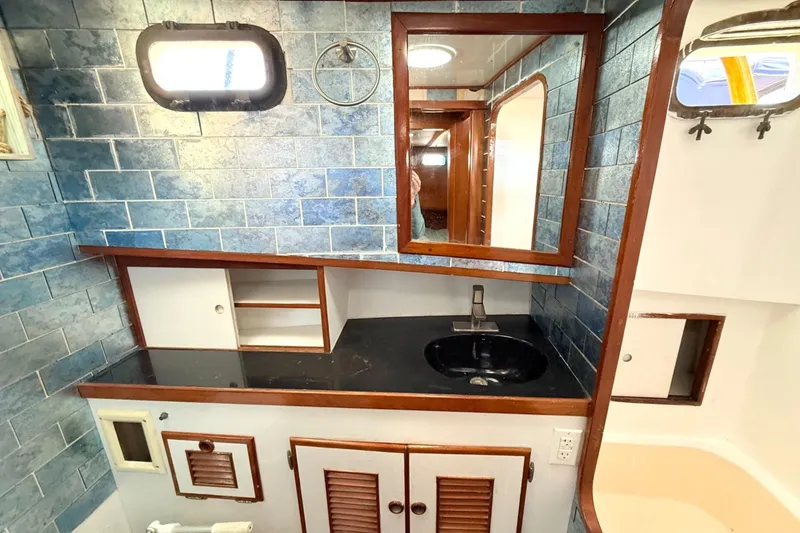 Slide: The Image of 1978 Marine Trader Europa bathroom with blue tile, mirror, and sink. - 25