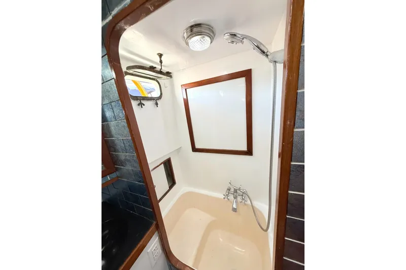 Slide: The Image of 1978 Marine Trader Europa yacht bathroom with shower, wooden trim, and nautical window. - 28