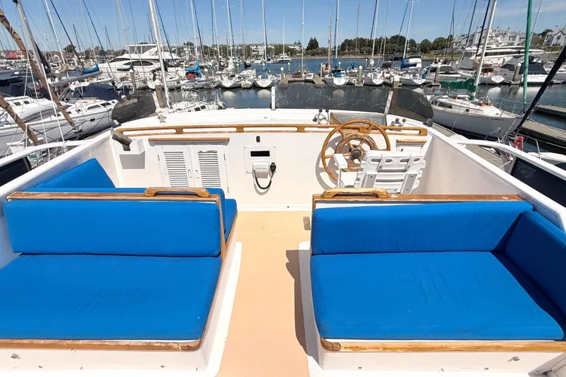 Slide: The Image of 1978 Marine Trader Europa boat deck with blue seating and wooden steering wheel in marina. - 9