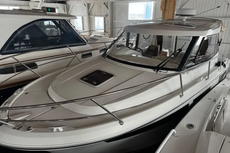 Slide: The Image of 2016 Jeanneau Merry Fisher 855 boat in a marina, showcasing sleek design and modern features. - 11