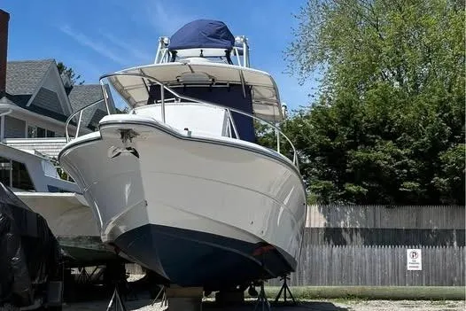 Slide: The Image of 2005 Stamas 310 Tarpon boat on land, with blue canopy, in a residential area. - 11
