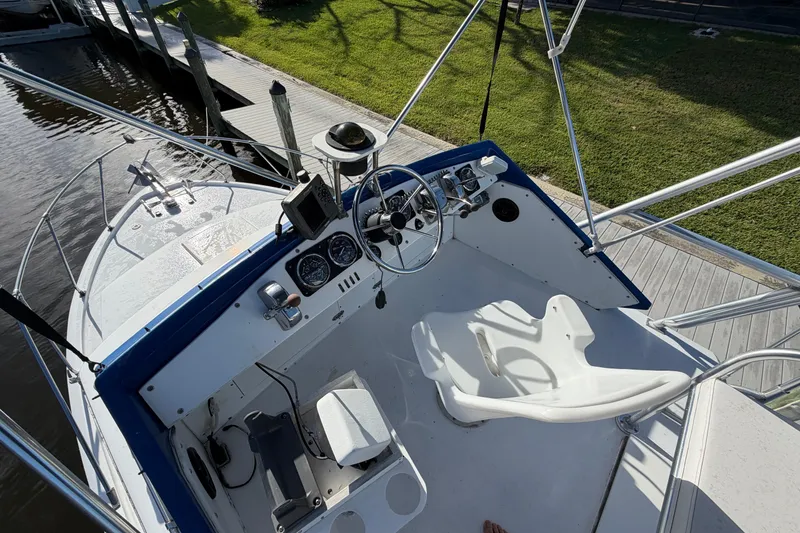 Slide: The Image of 1973 Chris-Craft 30 Tournament FB boat helm with steering wheel and gauges, docked by grassy area. - 6