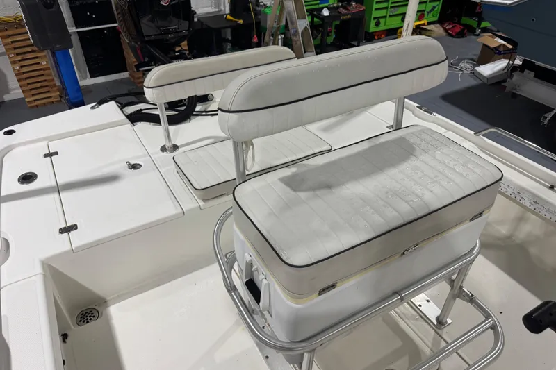 Slide: The Image of 2017 Mako 21 LTS boat interior with white cushioned seating and storage compartments. - 9