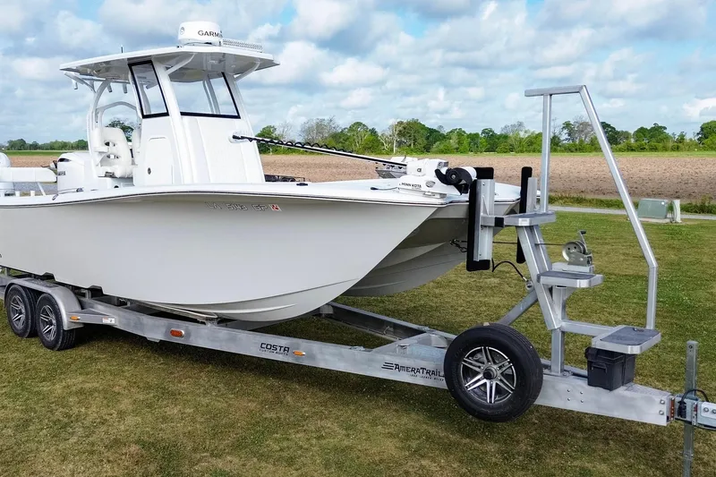 Slide: The Image of 2022 Costa Custom Boats 264 HC on trailer, parked on grassy field under cloudy sky. - 10