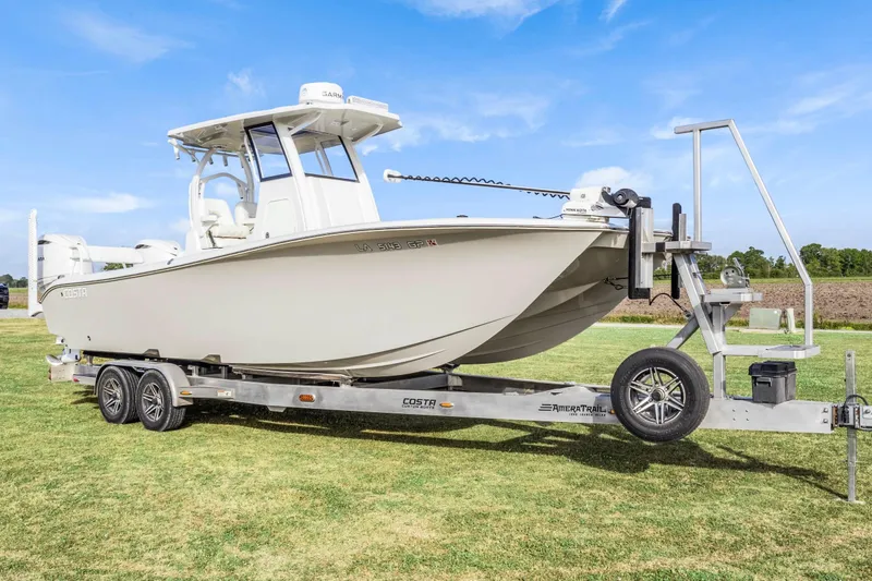 Slide: The Image of 2022 Costa Custom Boats 264 HC on trailer, parked on grass under clear blue sky. - 12