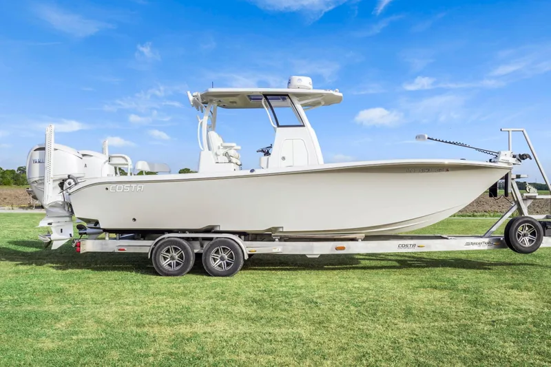 Slide: The Image of 2022 Costa Custom Boats 264 HC on trailer, displayed on grass under blue sky. - 2