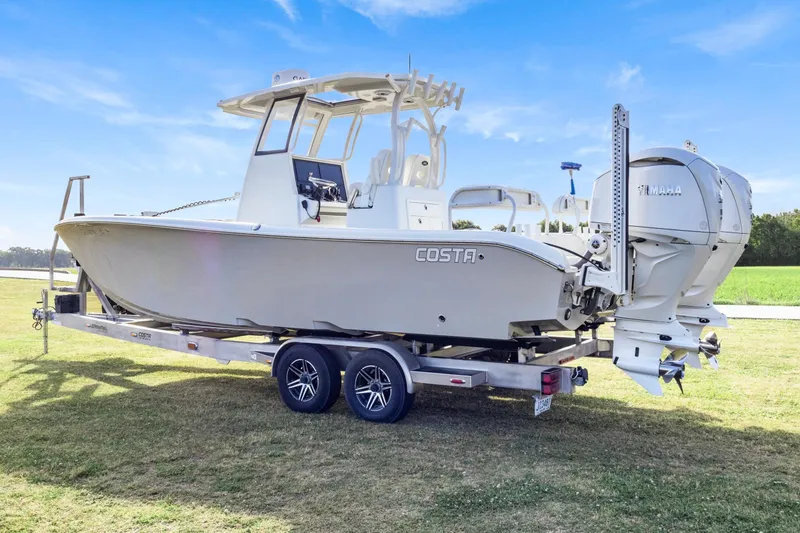 Slide: The Image of 2022 Costa Custom Boats 264 HC on trailer, featuring dual Yamaha outboard engines, parked on grass. - 7