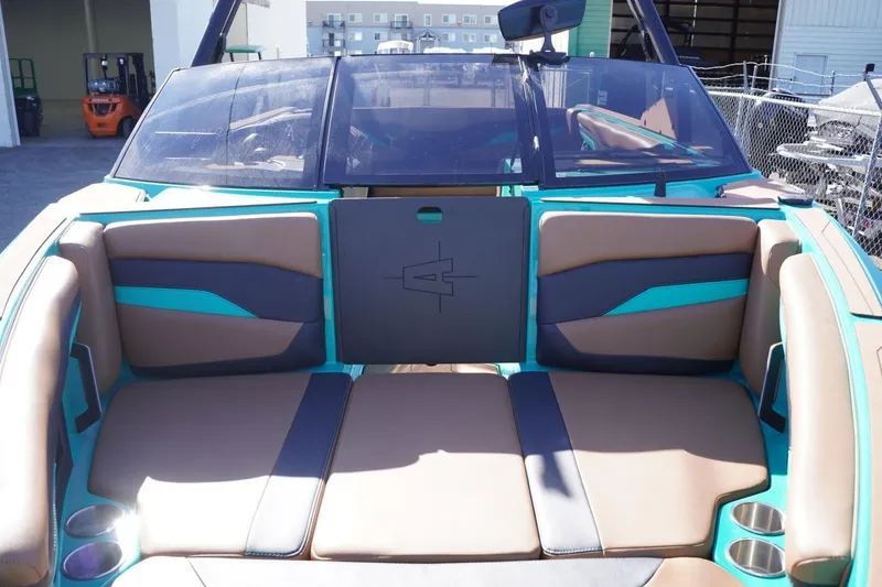 Slide: The Image of 2023 Axis T235 boat interior with tan and teal seating, cup holders, and windshield. - 16
