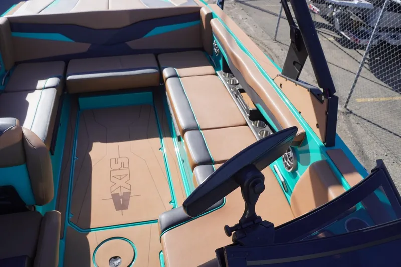 Slide: The Image of 2023 Axis T235 boat interior with tan and teal seating, cup holders, and steering wheel. - 27
