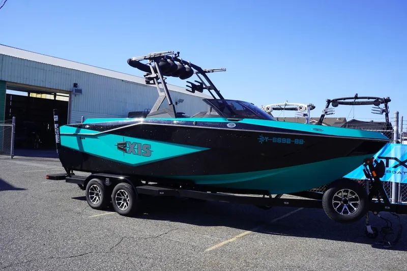 Slide: The Image of 2023 Axis T235 boat in teal and black on a trailer outside a warehouse. - 3