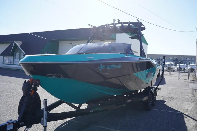 Slide: The Image of 2023 Axis T235 boat on trailer, teal and black design, parked outdoors. - 5