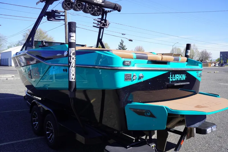 Slide: The Image of 2023 Axis T235 boat in vibrant teal, parked on a trailer in a lot. - 6