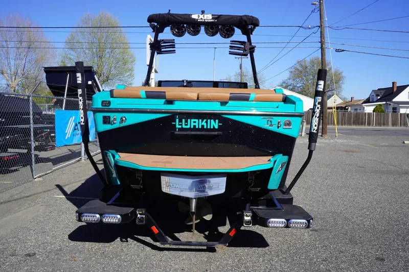 Slide: The Image of 2023 Axis T235 boat with teal and black design, parked outdoors. - 8