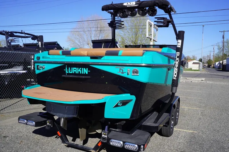 Slide: The Image of 2023 Axis T235 boat in vibrant turquoise and black, parked outdoors on a trailer. - 9