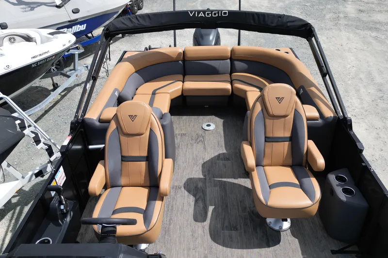 Slide: The Image of 2025 Viaggio Lago X-U 24 boat interior with tan and gray seating, docked outdoors. - 13
