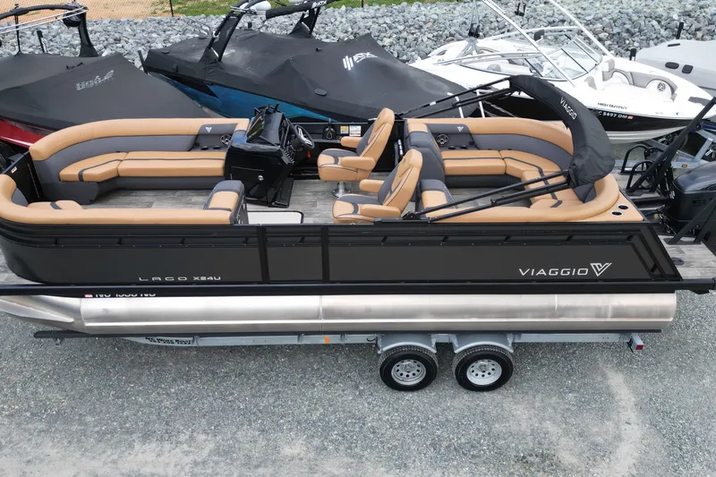 Slide: The Image of 2025 Viaggio Lago X-U 24 pontoon boat with tan seating, docked on a trailer. - 19