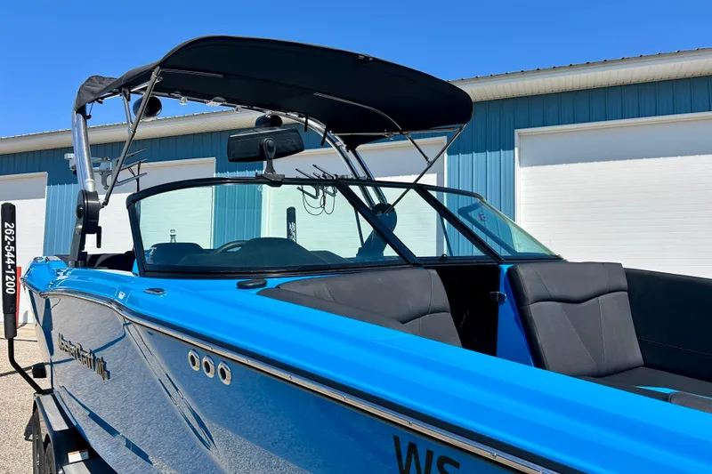 Slide: The Image of 2021 MasterCraft NXT24 boat with blue exterior, parked near a blue building. - 13