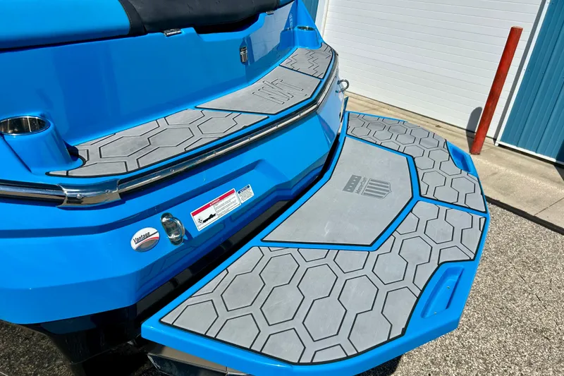 Slide: The Image of 2021 MasterCraft NXT24 boat with blue and gray hexagonal deck design. - 14