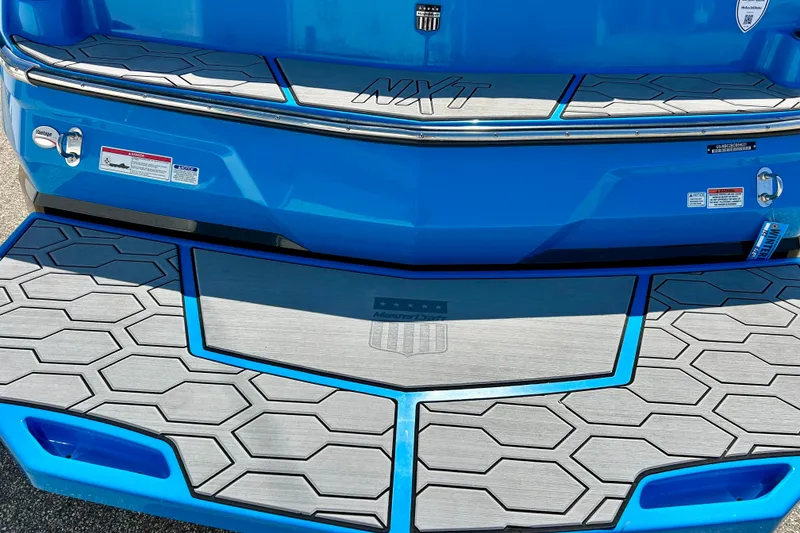 Slide: The Image of 2021 MasterCraft NXT24 boat with blue and gray hexagonal deck design. - 17