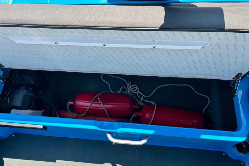 Slide: The Image of Open storage compartment in 2021 MasterCraft NXT24 boat with red fenders inside. - 38