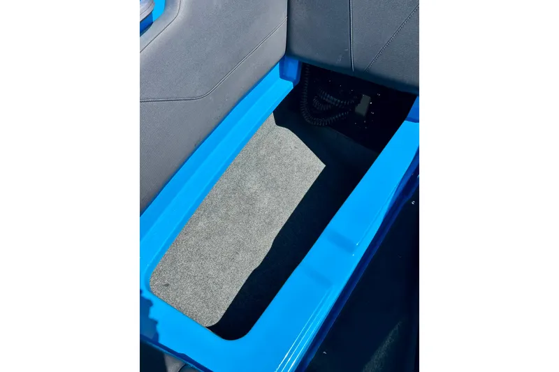 Slide: The Image of Interior storage compartment of 2021 MasterCraft NXT24 boat, featuring blue trim and gray carpet. - 47