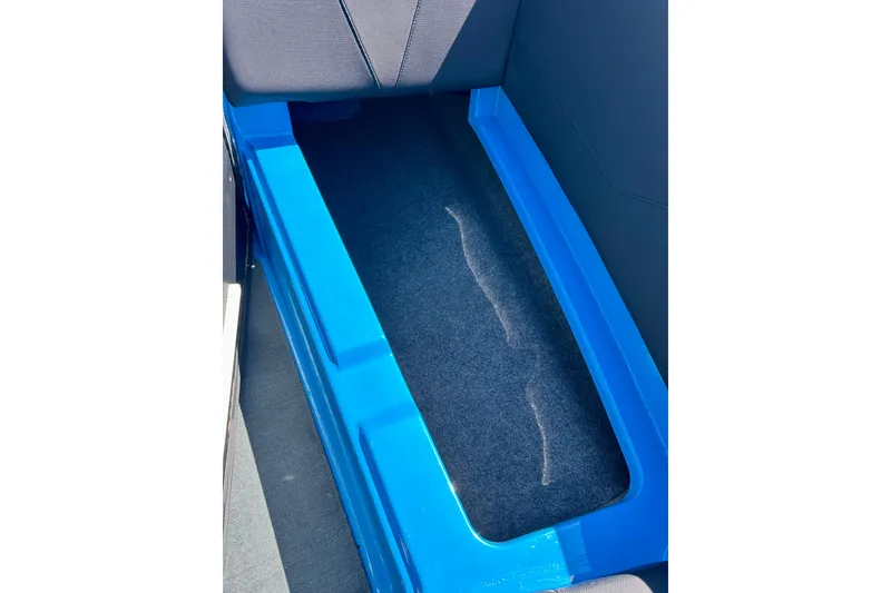 Slide: The Image of 2021 MasterCraft NXT24 boat storage compartment with blue trim and carpeted interior. - 49